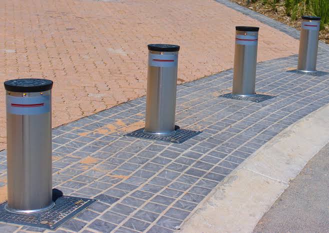 Stainless steel rising bollards installed across a paved entrance