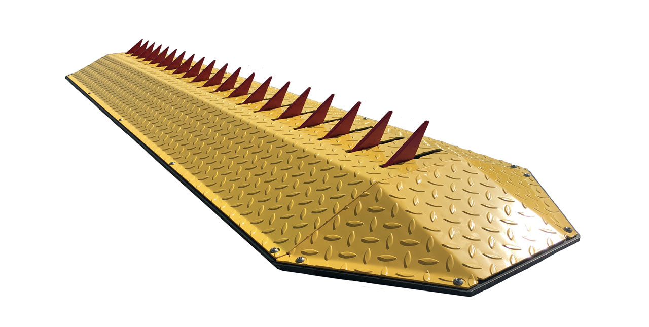 Tyre killer spike barrier with raised red spikes on a chequer plate base